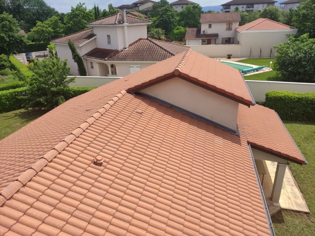 Toit en tuiles sur une maison, avec un jardin verdoyant à Toulouse, rénovation énergétique.